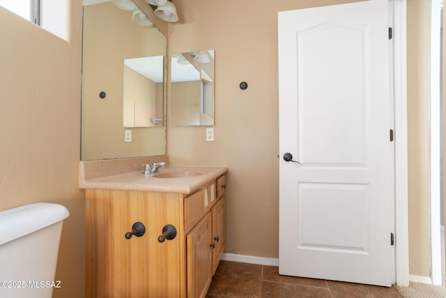 half bathroom featuring toilet, vanity, and baseboards