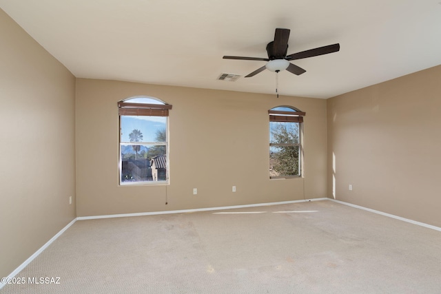 unfurnished room featuring light colored carpet, visible vents, baseboards, and ceiling fan