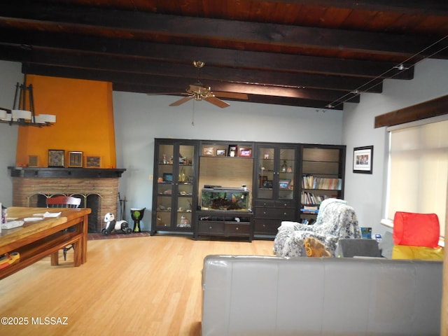 living area with a fireplace, wood finished floors, beam ceiling, and a ceiling fan