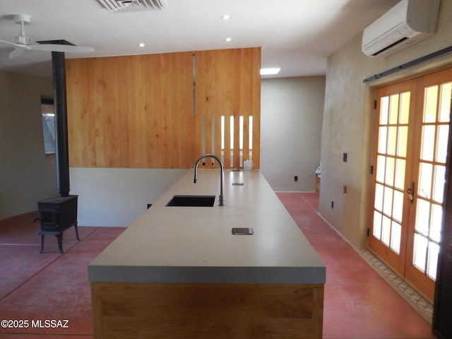 kitchen with a wall unit AC, a sink, visible vents, french doors, and a wood stove