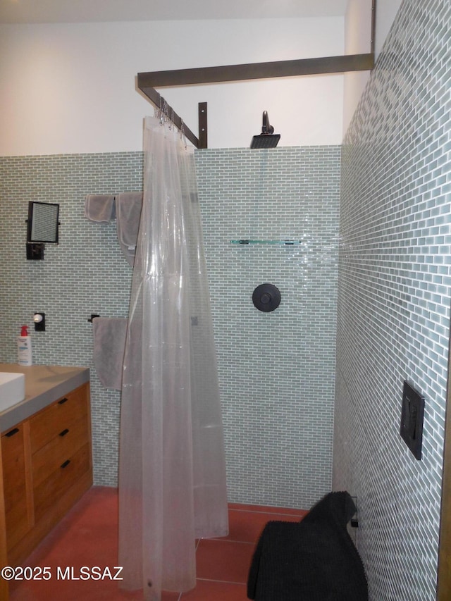 bathroom with vanity, a tile shower, and tile walls