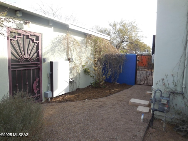 view of property exterior with fence, a gate, and stucco siding