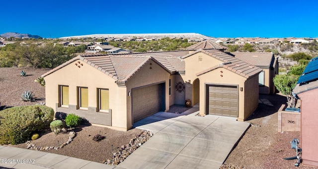 mediterranean / spanish-style house with driveway, an attached garage, a tiled roof, and stucco siding