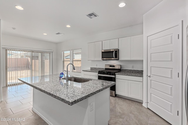 kitchen with stainless steel appliances, sink, a center island with sink, and white cabinets