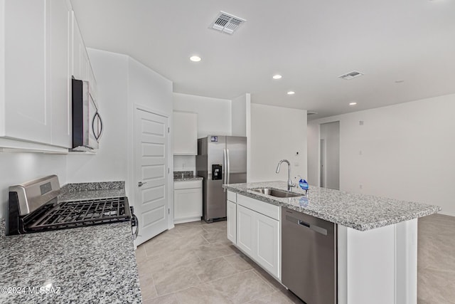 kitchen featuring sink, white cabinetry, light stone counters, a center island with sink, and stainless steel appliances