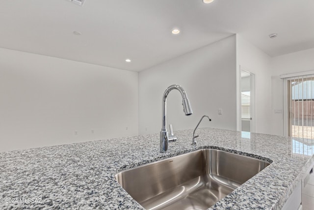 interior details featuring sink and light stone countertops