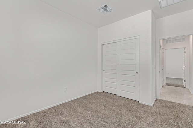 unfurnished bedroom featuring light colored carpet and a closet