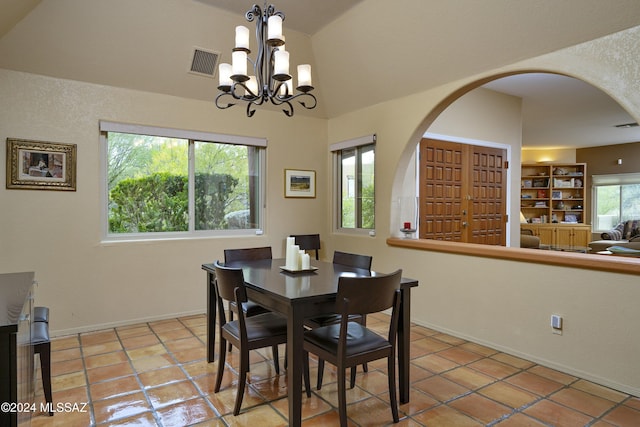 dining area with vaulted ceiling, light tile patterned floors, and an inviting chandelier