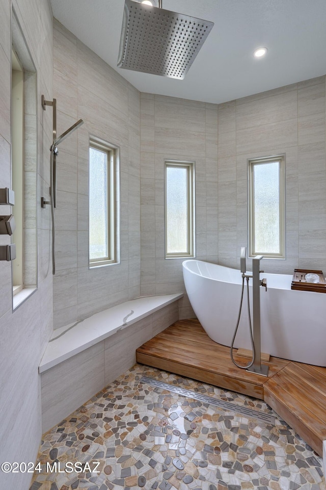 bathroom featuring tile walls, plenty of natural light, and separate shower and tub