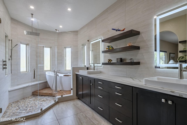 bathroom with vanity, plus walk in shower, tile patterned flooring, and tile walls