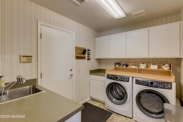 washroom with cabinets, sink, a textured ceiling, and washing machine and clothes dryer