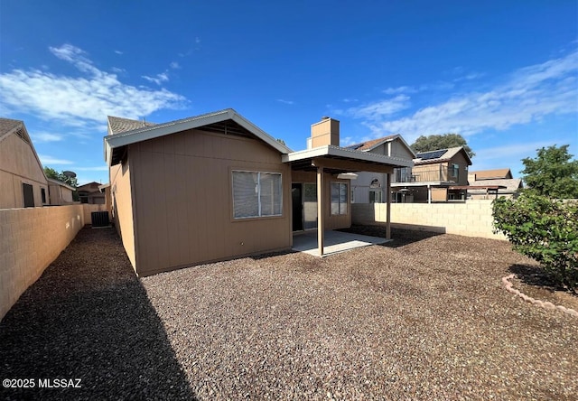 back of house featuring central AC, a patio, a chimney, and a fenced backyard