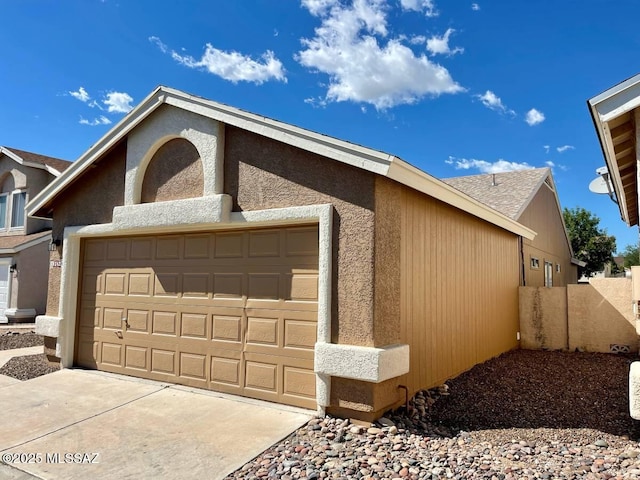 view of front of property with concrete driveway, an attached garage, and stucco siding