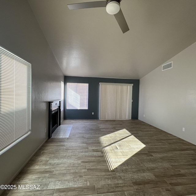 unfurnished living room with vaulted ceiling, ceiling fan, wood finished floors, and visible vents