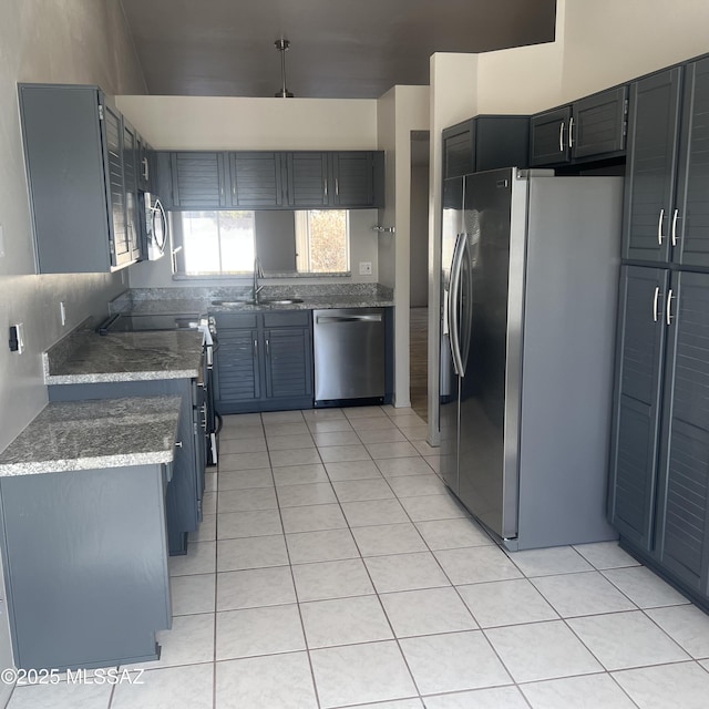 kitchen with light tile patterned floors, stainless steel appliances, stone countertops, and a sink