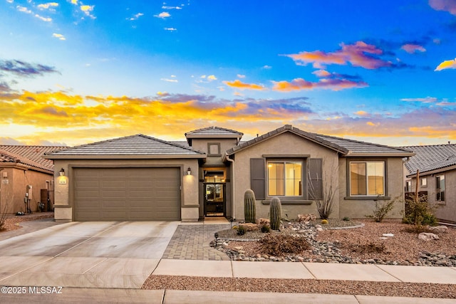 view of front of house featuring concrete driveway, a tile roof, an attached garage, and stucco siding