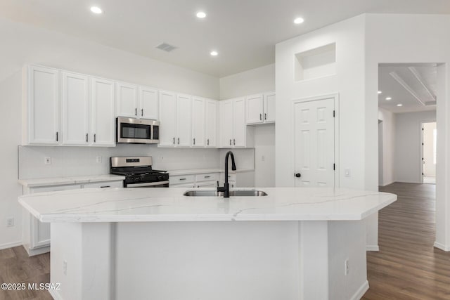 kitchen featuring appliances with stainless steel finishes, sink, light stone counters, white cabinets, and an island with sink