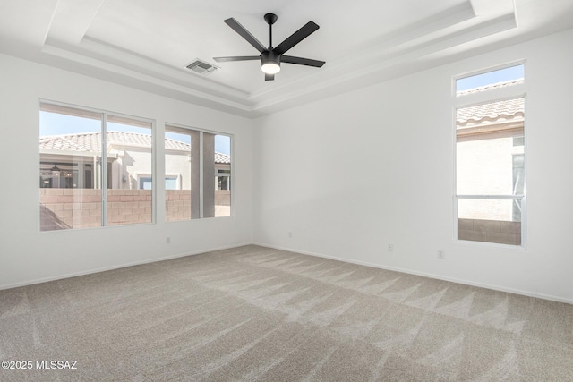 carpeted empty room with ceiling fan and a tray ceiling