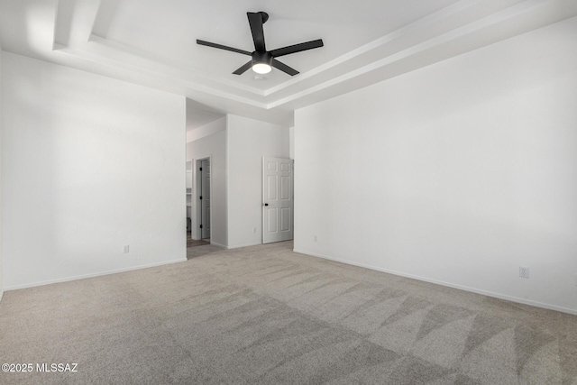 carpeted empty room featuring a tray ceiling and ceiling fan