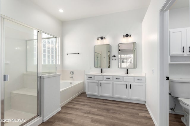 full bathroom with toilet, vanity, plus walk in shower, and wood-type flooring