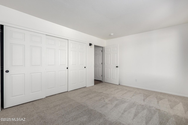 unfurnished bedroom with a closet and light colored carpet