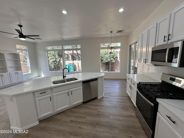 kitchen with sink, appliances with stainless steel finishes, white cabinetry, backsplash, and hardwood / wood-style floors