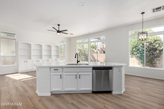 kitchen with a center island with sink, sink, pendant lighting, stainless steel dishwasher, and white cabinets