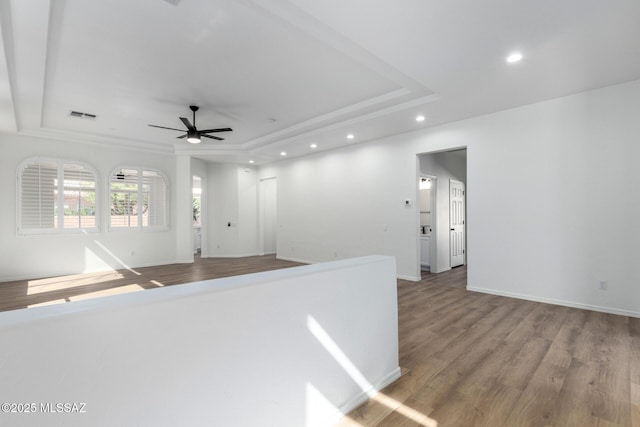 interior space with ceiling fan, a raised ceiling, and hardwood / wood-style floors