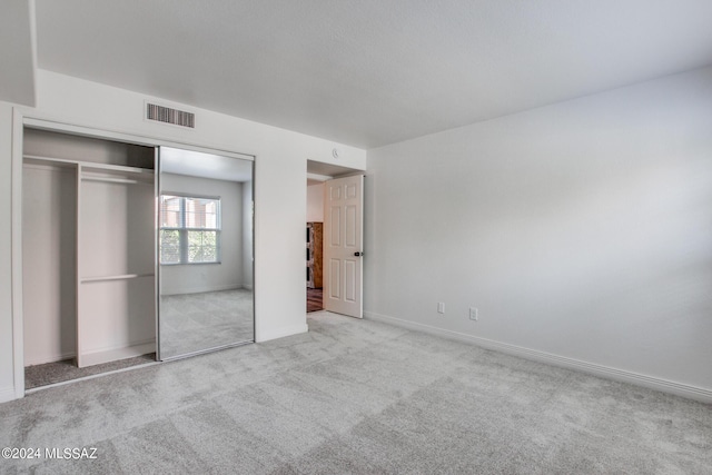 unfurnished bedroom with light colored carpet and a closet