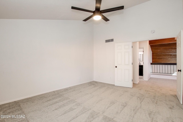 empty room featuring ceiling fan, light colored carpet, and high vaulted ceiling