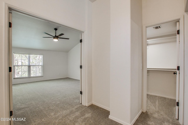 hallway with vaulted ceiling and light colored carpet