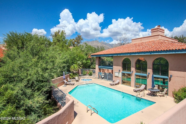 view of pool featuring a mountain view, a patio area, and a community hot tub