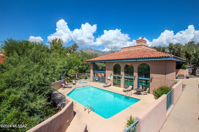 view of swimming pool featuring a hot tub, a mountain view, and a patio