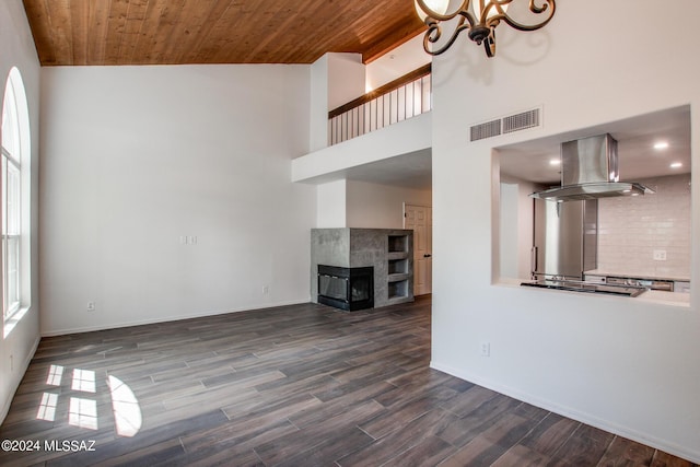 unfurnished living room featuring wood ceiling, an inviting chandelier, dark hardwood / wood-style floors, a high ceiling, and a multi sided fireplace