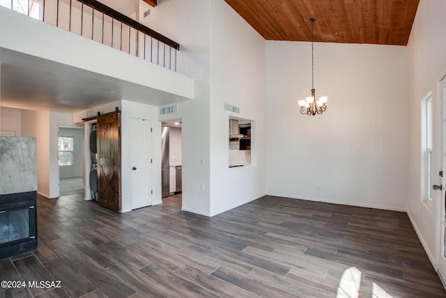 unfurnished living room featuring dark hardwood / wood-style floors, wood ceiling, a barn door, and an inviting chandelier