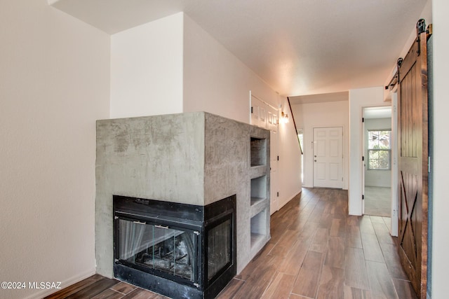 kitchen featuring a multi sided fireplace, a barn door, and dark wood-type flooring