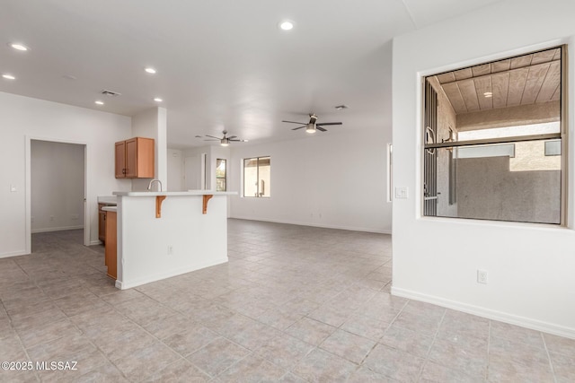 kitchen with ceiling fan, a kitchen breakfast bar, kitchen peninsula, and sink