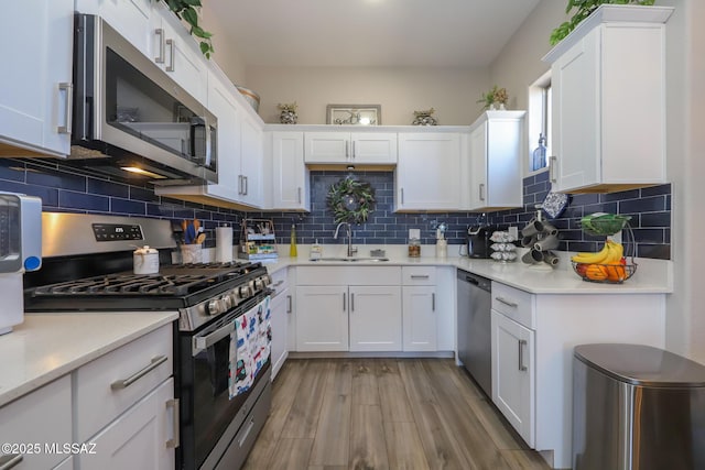 kitchen with white cabinetry, stainless steel appliances, light hardwood / wood-style floors, and sink