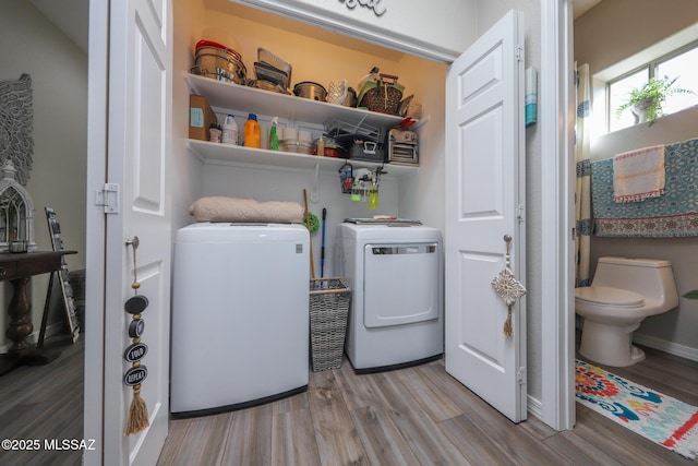 clothes washing area with washing machine and dryer and light hardwood / wood-style floors