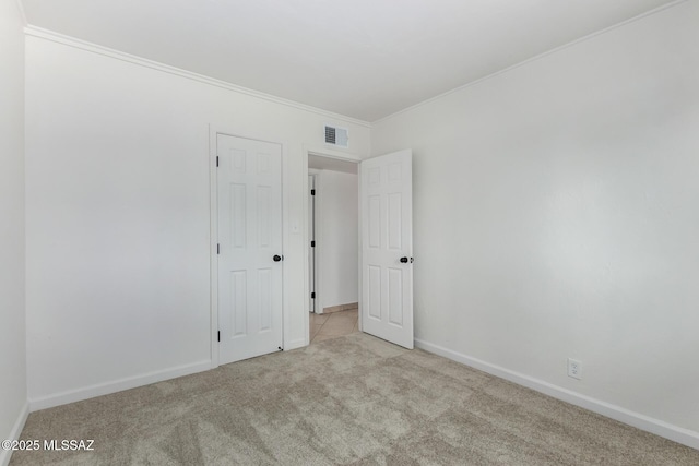 spare room with ornamental molding and light carpet