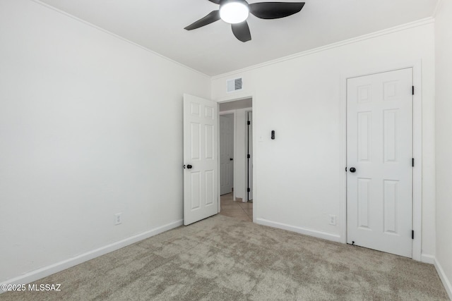 unfurnished bedroom featuring ornamental molding, light colored carpet, and ceiling fan