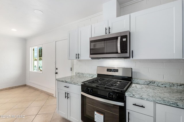 kitchen with tasteful backsplash, appliances with stainless steel finishes, light tile patterned floors, and white cabinets