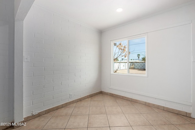 spare room with brick wall, ornamental molding, and light tile patterned floors