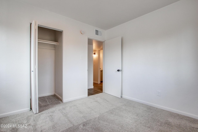 unfurnished bedroom featuring light colored carpet and a closet