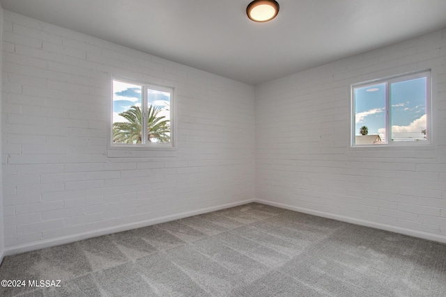 spare room featuring brick wall and carpet