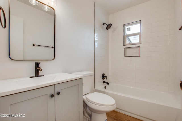 full bathroom with hardwood / wood-style flooring, vanity, tiled shower / bath, and toilet