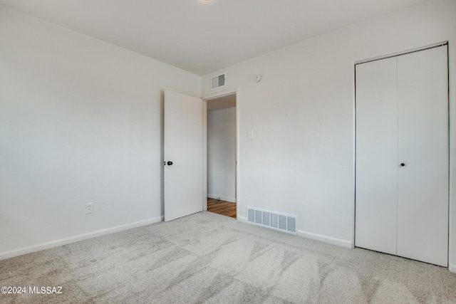 unfurnished bedroom with light carpet and a closet