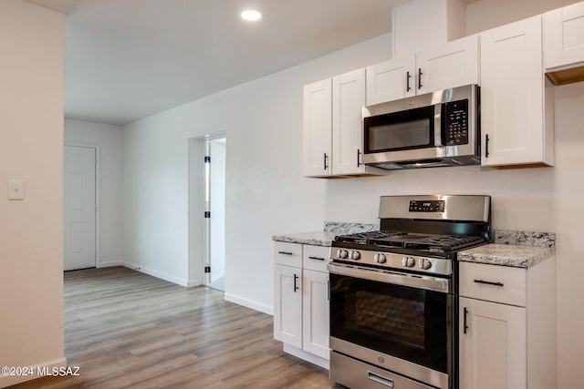 kitchen with light stone countertops, appliances with stainless steel finishes, and white cabinets