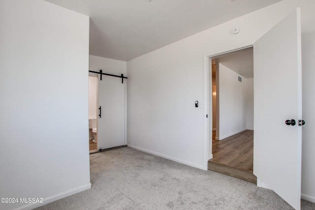 carpeted empty room with a barn door