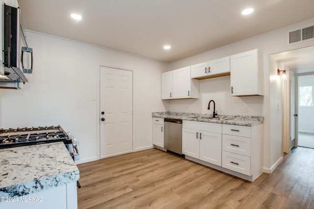 kitchen featuring dishwasher, sink, white cabinets, light stone countertops, and light wood-type flooring